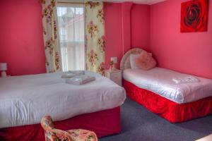 大雅茅斯Villa Rose的配有粉红色墙壁和椅子的客房内的两张床