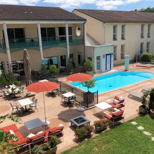 卡斯特尔卡斯特尔奥希坦美居酒店的一个带桌子和遮阳伞的户外庭院和一个游泳池
