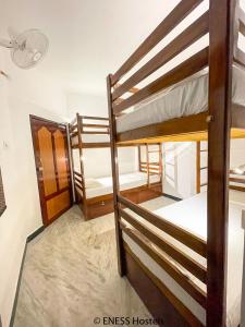 蓬蒂切里Eness Hostels Pondicherry的带三张双层床和一扇门的房间