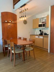 拉姆吉Appartement 2 chambres en duplex à La Mongie的厨房以及带木桌和椅子的用餐室。