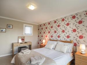 LybsterRose Cottage的一间卧室配有一张带花卉壁纸的床