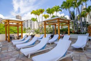 檀香山Luana Waikiki #710的棕榈树庭院里的一排椅子和遮阳伞