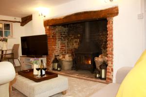 法拉姆灵厄姆Romantic* Castle on the Hill Cottage *Framlingham的客厅设有壁炉和电视。