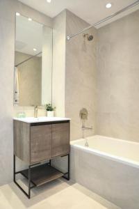 布朗克斯Global Luxury Suites at The Arches的一间带水槽、浴缸和镜子的浴室