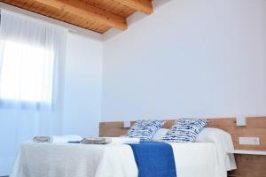 Les Coves de VinromaCasa Rural Cal Saboner的一间卧室配有两张带白色和蓝色枕头的床