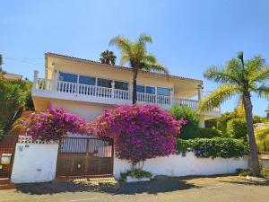 绍萨尔Villa Carioca - with private pool, marvelous garden and amazing ocean view的围栏前有紫色花朵的房子