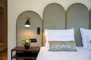 博尔扎诺斯塔德特希塔酒店的卧室配有一张带花瓶的大型白色床