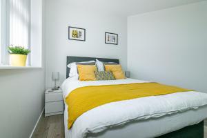 哈特菲尔德Executive Apartment Close to Station的白色卧室配有一张带黄色枕头的大床