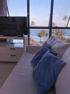 嘎林海斯港Marulhos Resort Flat Vista Mar的一张带蓝色枕头的床和一台电视机