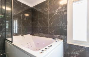 第戎L'étoile et le Merveilleux 2 appartements SPA的黑色瓷砖浴室设有浴缸和窗户。