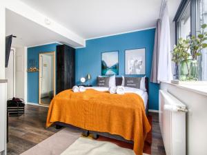 慕尼黑limehome München的一间卧室设有蓝色的墙壁和一张带橙色毯子的床。