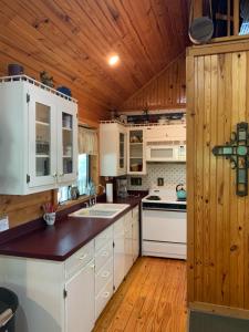Lakewood HarborLake Whitney Log Cabin的厨房配有白色橱柜和木制天花板