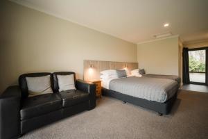因弗卡吉尔Invercargill Holiday Park & Motels的一间卧室配有一张床、一张沙发和一把椅子