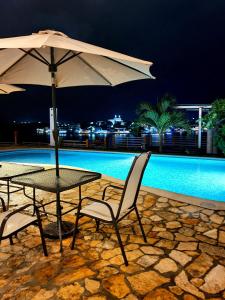 弗洛勒斯APARTHOTEL VISTA LAGO的游泳池旁配有遮阳伞的桌椅