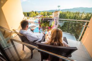 多布瓦Terme Paradiso - Hotel Paradiso的坐在阳台的男人和女人,看着游泳池