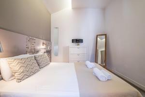丰沙尔Cayres Suites Carmo的一间卧室配有一张大床和两条白色毛巾