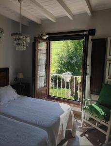 Poo de CabralesLa Gesta Picos de Europa的一间卧室设有一张床、一个窗口和一把椅子