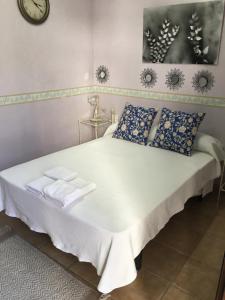 埃尔卡斯蒂略德拉斯瓜尔达斯阿巴荷乡村旅馆的一张带蓝色枕头的白色床和墙上的时钟