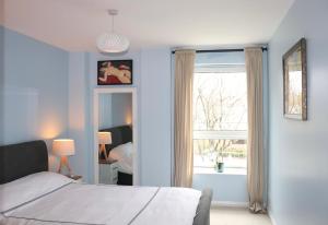 爱丁堡Luxflat - Port Of Leith - Free Parking的一间拥有蓝色墙壁的卧室、一张床和窗户
