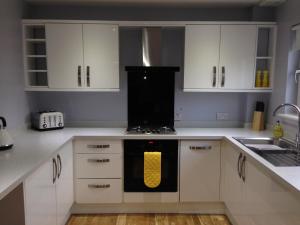 东基尔布赖德Flat Three, 212 Eaglesham Road, East Kilbride, Glasgow的厨房配有白色橱柜和黄色烤箱