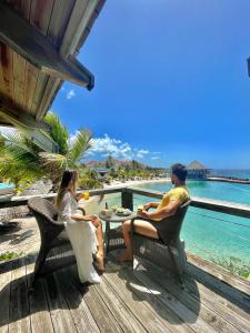 威廉斯塔德库拉索阿维拉海滨酒店的两人坐在甲板上的桌子上,俯瞰大海