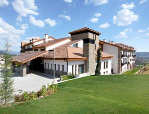巴达古斯Hotel & Spa Real Badaguás Jaca的山丘上带绿色草坪的房子
