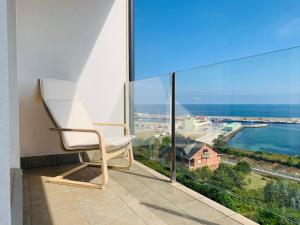 布里拉蒂卡波Apartamentos la Marosa Delux的白色椅子坐在阳台,眺望着大海