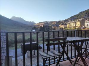 坎丹奇奥Apartamentos Pirineos Rent的阳台配有桌子、两把椅子和烧烤架。