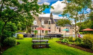 戴斯Pinehurst Lodge Hotel - Aberdeen的房屋前设有带野餐桌和遮阳伞的花园