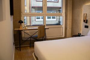 拉科鲁尼亚Hotel Alda Orzán的一间卧室配有一张床、一张书桌和一个窗户。