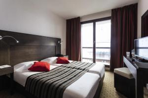 蒂涅Hôtel Tignes Le Diva的酒店客房配有一张带红色枕头的大床