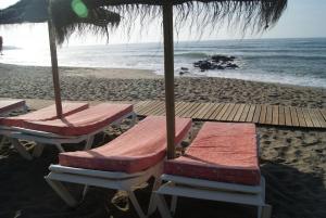 卡拉德米哈斯Apartamentos La Dorada的海滩上的2把躺椅和1把遮阳伞