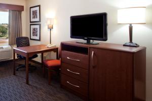 麦卡莱斯特AmericInn by Wyndham McAlester的酒店客房的梳妆台配有电视和书桌
