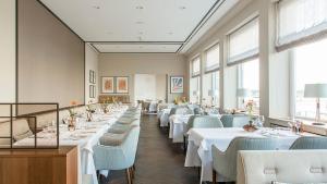 波恩AMERON Bonn Hotel Königshof的用餐室配有白色的桌子和蓝色的椅子