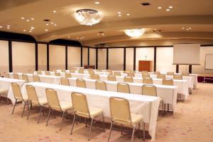 一关Hotel Matsunoka Ichinoseki的一间会议室,配有白色的桌椅和讲台