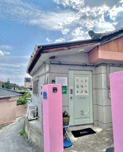 江陵市Saesori Guesthouse的一个小房子外的粉红色冰箱