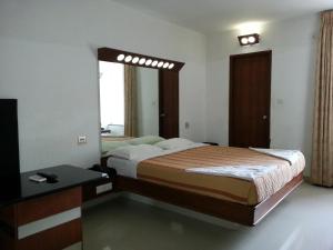 蓬蒂切里莲花湾景酒店的一间卧室配有一张床、一张桌子和一面镜子