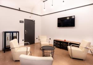 卢布尔雅那阿德霍克青年旅舍的客厅配有白色椅子和平面电视