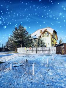 戈鲁别Willa Zamkowisko z ogrodowym jacuzzi的雪中带白色围栏的房子