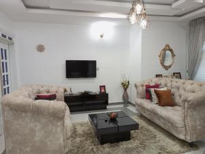 瓦里E - Glisters Home的客厅配有两张沙发和一台电视机