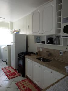 邦比尼亚斯Apto. 2 quartos em Bombinhas (60 m da praia)的厨房配有白色橱柜、水槽和冰箱。
