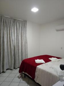邦比尼亚斯Apto. 2 quartos em Bombinhas (60 m da praia)的一间卧室配有一张带红色毯子的床和窗户。