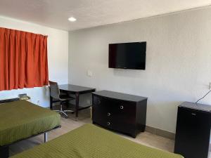 霍布斯Executive Inn的酒店客房配有一张床、一张书桌和一台电视。
