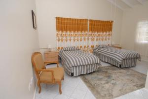 Micoud扎马克住宿加早餐旅馆的一间卧室配有两张床、一张桌子和一把椅子