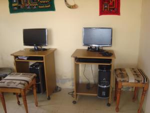 Comunidad YumaniIMPERIO del SOL的一间设有两张桌子的房间,配有两张显示器和两把椅子