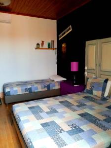 费雷拉杜阿连特茹Pátio das Andorinhas的一间卧室配有两张床和一个紫色的床头柜