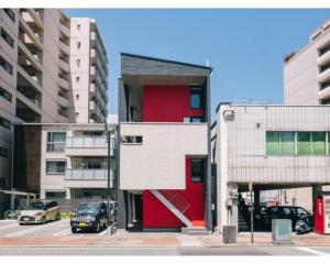 熊本REQRAS Sakuramachi - Vacation STAY 45081v的城市里一座红色和白色的建筑,有汽车