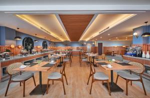 泗水ASTON Inn Jemursari的一间带木桌椅的餐厅和一间酒吧