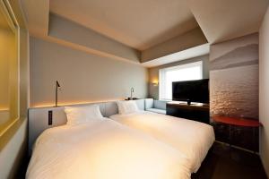 鹿儿岛remm Kagoshima的卧室配有一张白色大床和电视。