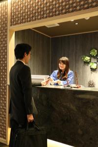 大阪J-SHIP大阪难波客舱胶囊旅馆的站在柜台上的男女